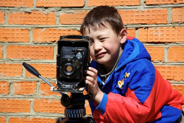 Ungen att göra ett skott med retro kamera på stativ — Stockfoto