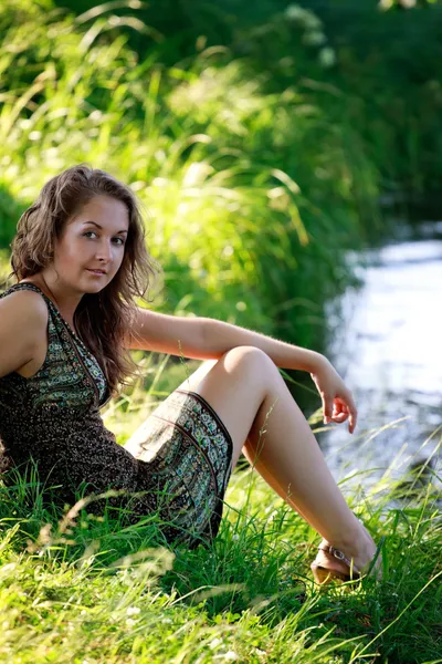 Kobieta siedzi na riverside — Zdjęcie stockowe