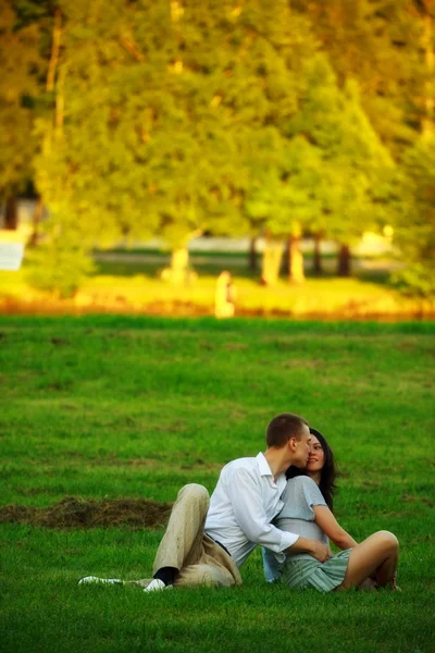 Young couple sitting on park lawn — Stock Photo, Image