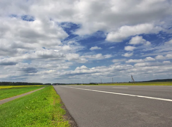 Autostrada sotto cielo nuvoloso blu — Foto Stock