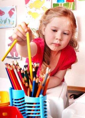 Child with pencil in play room. clipart
