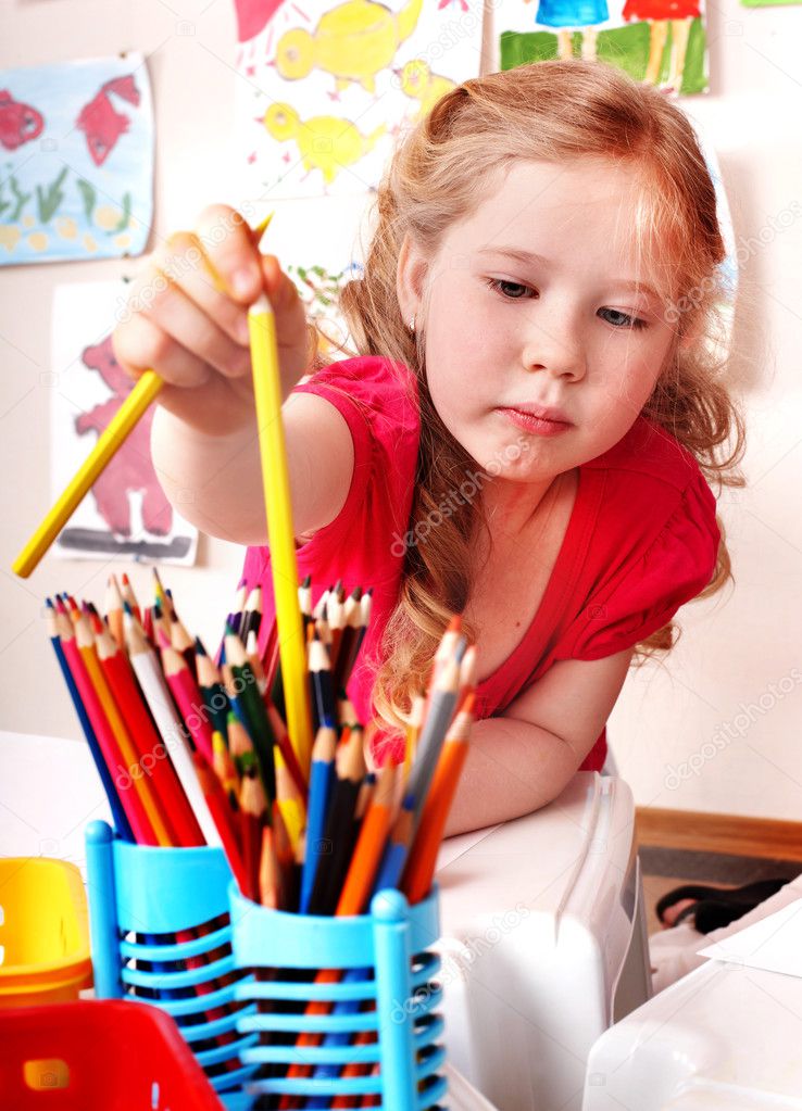 Child with pencil in play room.
