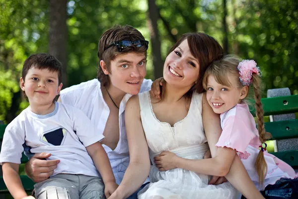 Família feliz e crianças de grupo no banco no parque . — Fotografia de Stock