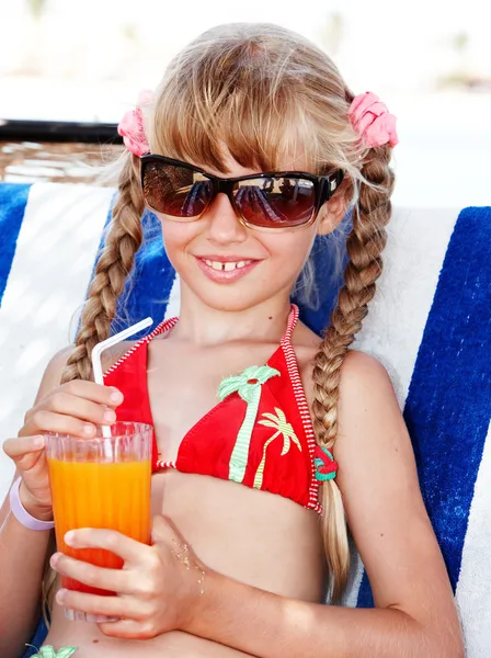 Child in sunglasses and red bikini drink juice. — Stock Photo, Image