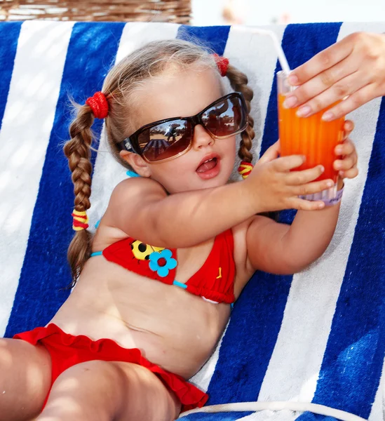 Barn flicka i glasögon och röda bikini dricka juice. — Stockfoto