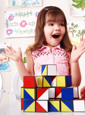 Child with wood block and construction set in play room. clipart