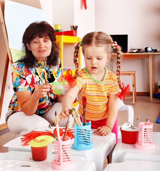 Child with teacher draw paints in playroom. — Stock Photo, Image