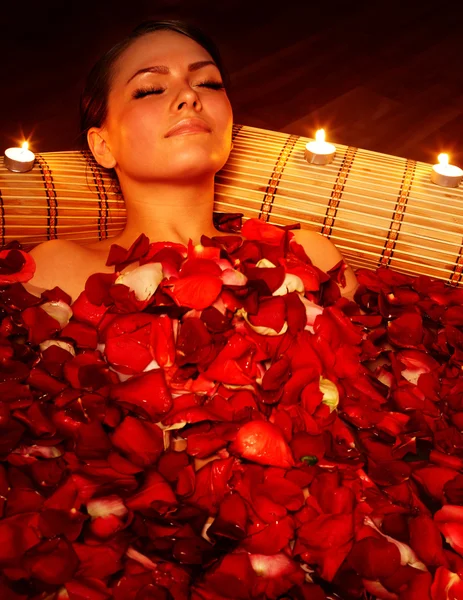 Красивая девушка в джакузи с лепестками роз и свечами . — стоковое фото
