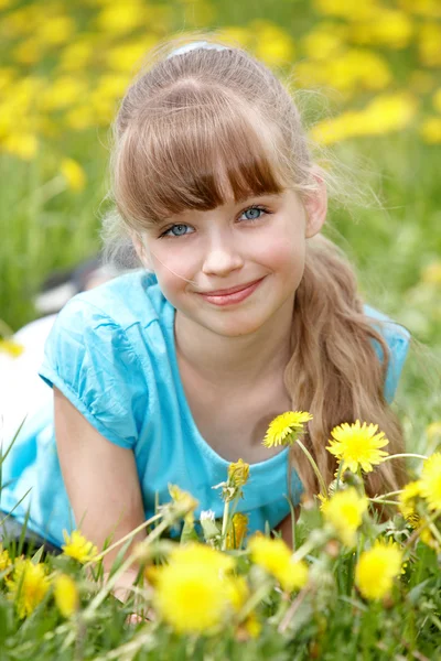 Klein meisje liggen op gras in bloem. — Stockfoto