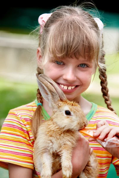 stock image Happy girl feed rabbit with carrot.