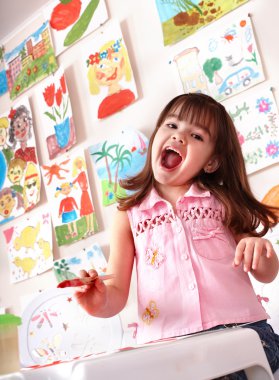 Little girl painting picture in preschool. clipart