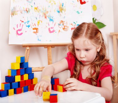 Child with wood block and construction set in play room. clipart