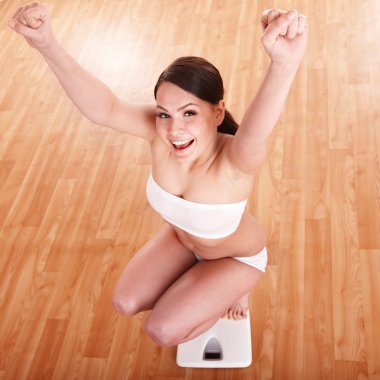 Happy girl on scales. Weight-loss. clipart