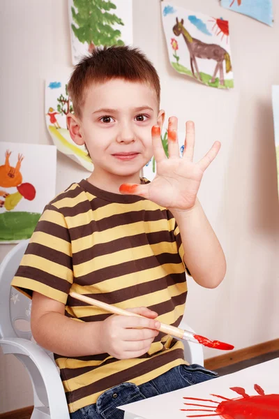 Kind met borstel tekenen rode zon in de speelkamer. — Stockfoto