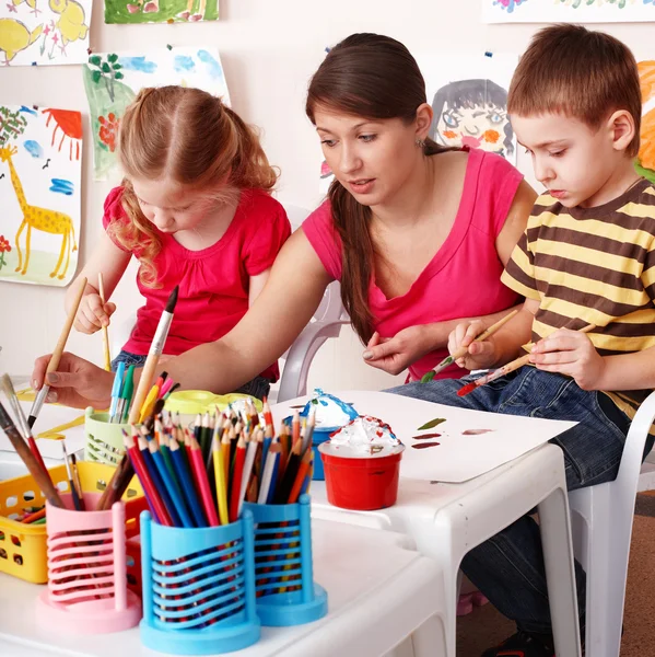 Öğretmen ile çocuk oyun odasında boyalar çizmek. — Stok fotoğraf