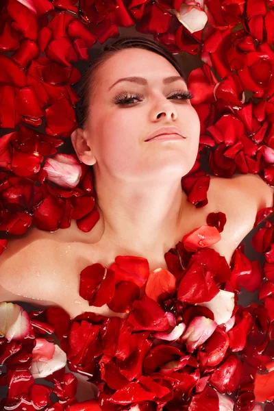 Mooi meisje in jacuzzi met roos bloemblad. — Stockfoto