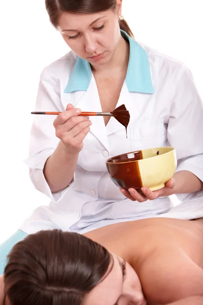 Girl having chocolate facial mask apply by beautician. — Stock Photo, Image