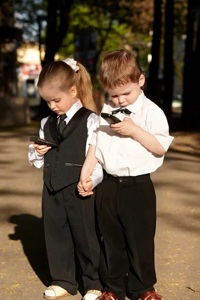Enfants en costume d'affaires avec téléphone portable à l'extérieur . — Photo