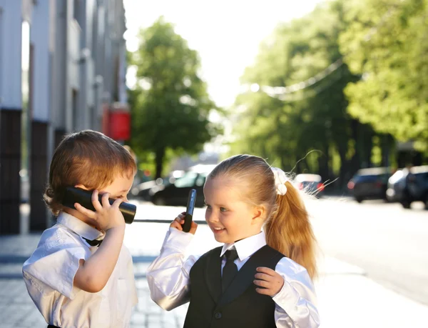 Τα παιδιά στην επιχείρηση που ταιριάζουν με το κινητό τηλέφωνο σε εξωτερικούς χώρους. — Φωτογραφία Αρχείου
