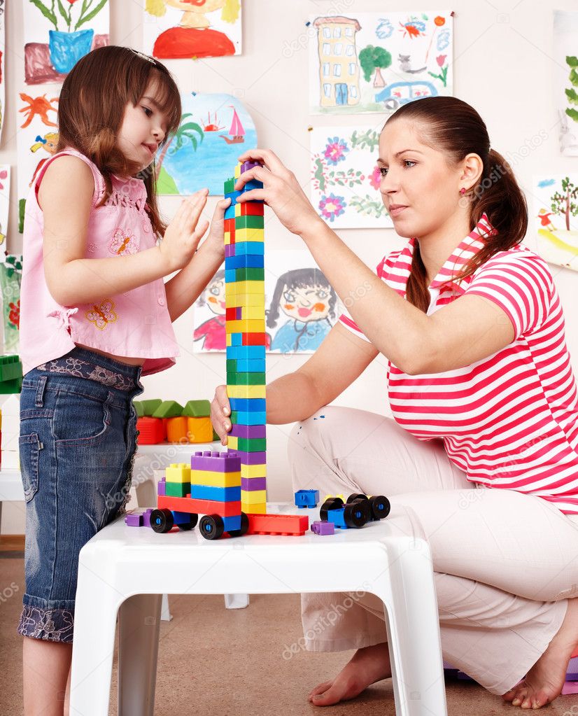 Child with wood block and construction set in play room.
