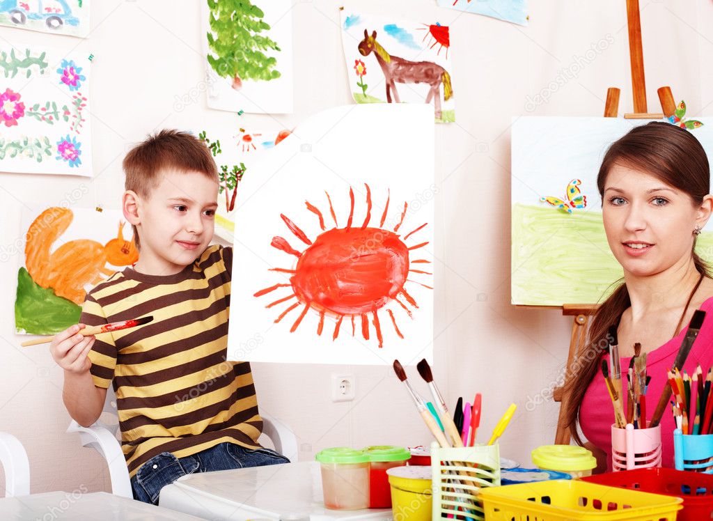 Child with teacher draw paint in play room.