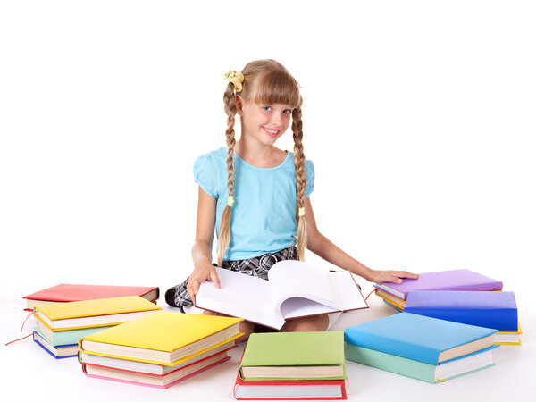 Child with pile of books reading on floor.