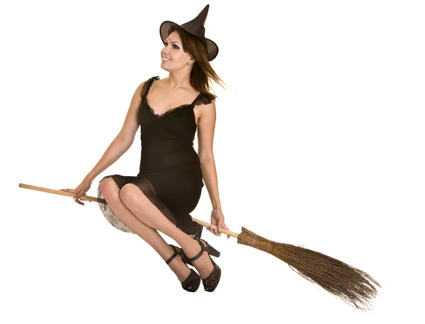 Halloween häxa blond i svart klänning och hatt på kvast. — Stockfoto