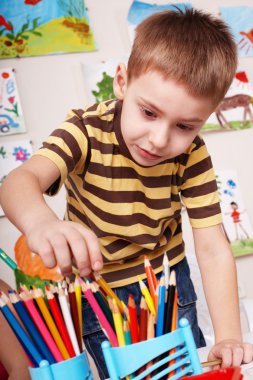 Child with pencil in play room. clipart