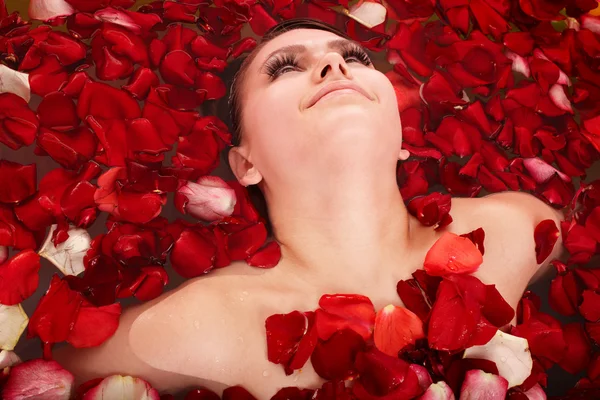 玫瑰的花瓣在按摩浴缸的漂亮女孩. — 图库照片