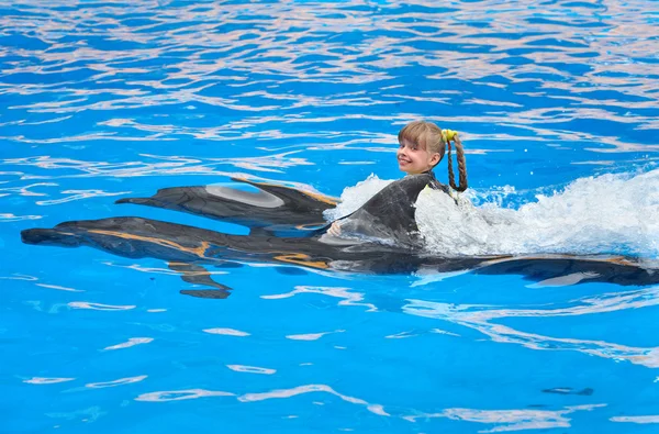Παιδί και δελφίνια που κολυμπούν στα γαλανά νερά. — Φωτογραφία Αρχείου