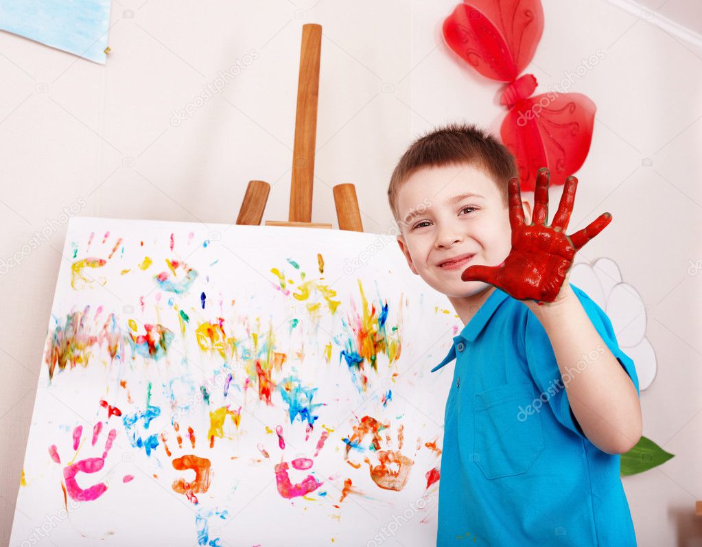 Child painting on easel by hands.