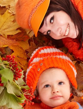 Happy family with child on autumn orange leaves. clipart