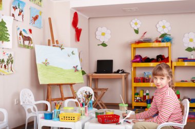 Child with picture and brush in playroom. clipart