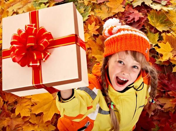 Girl in autumn orange hat on leaf and gift box. — Stock Photo, Image