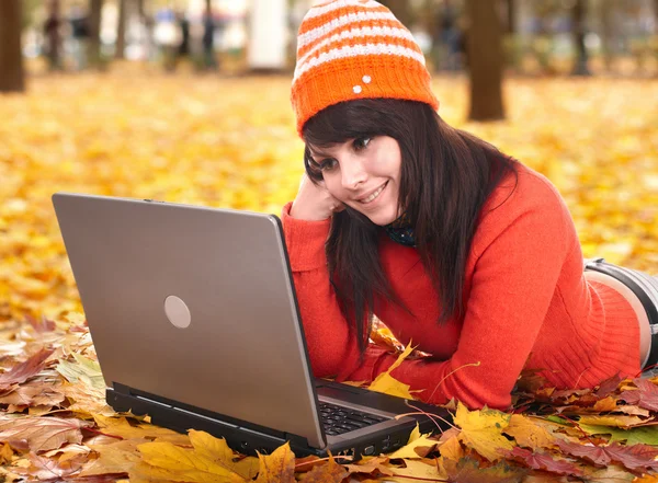 Girl in autumn orange leaves with laptop.Fall sale.