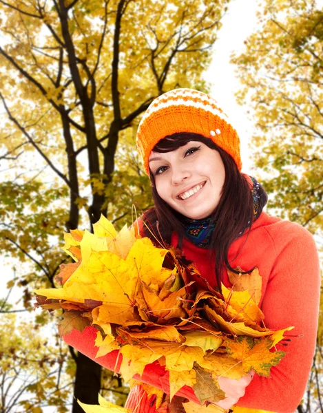 Dívka v podzimní oranžová čepice s listy skupina poblíž stromu. — Stock fotografie
