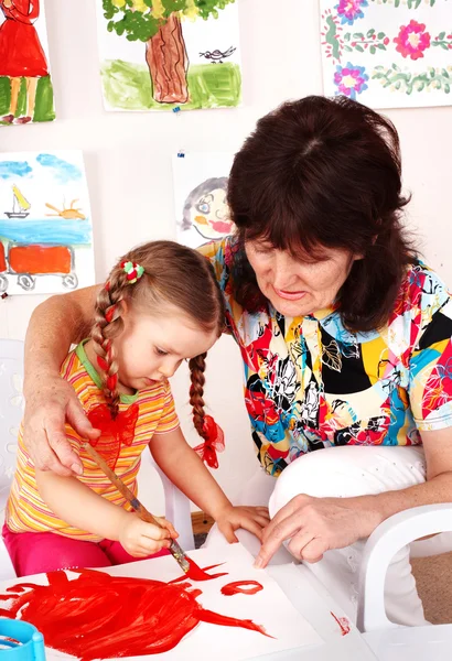 Bambino con insegnante disegnare vernici in sala giochi . Immagini Stock Royalty Free