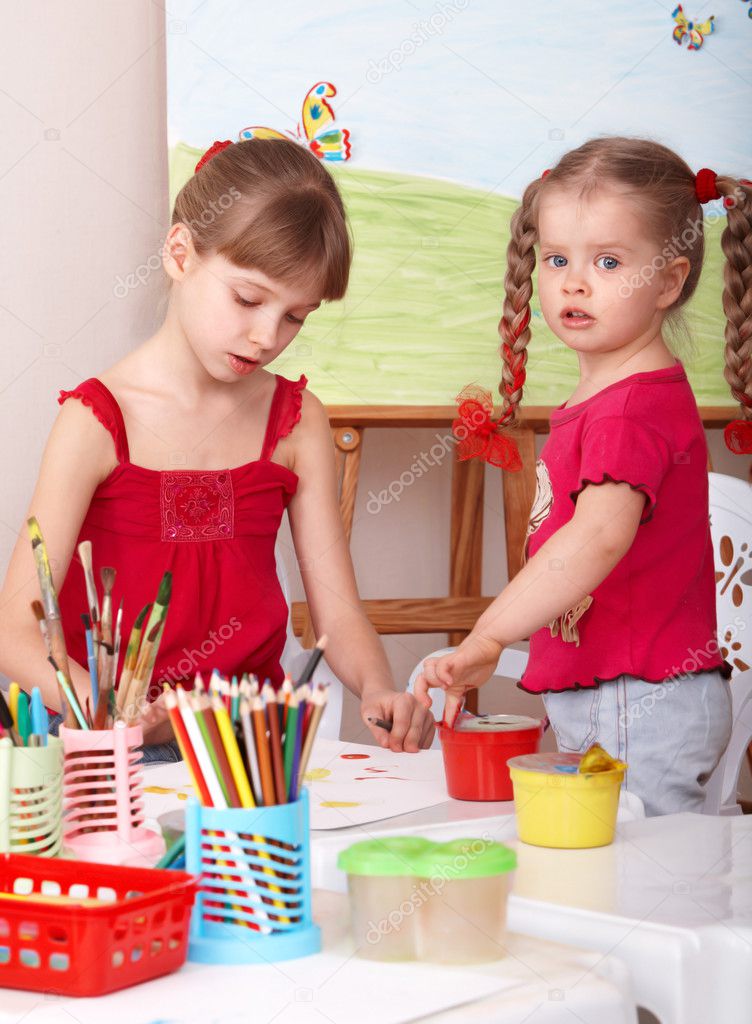 Child with picture and brush in playroom.