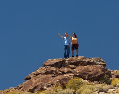 Hikers in desert point to distant object clipart
