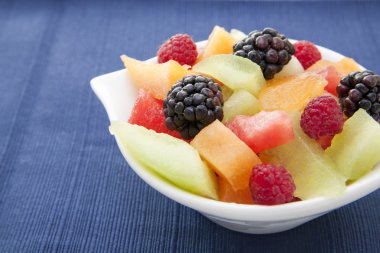 Berries and melon in a bowl on the table clipart