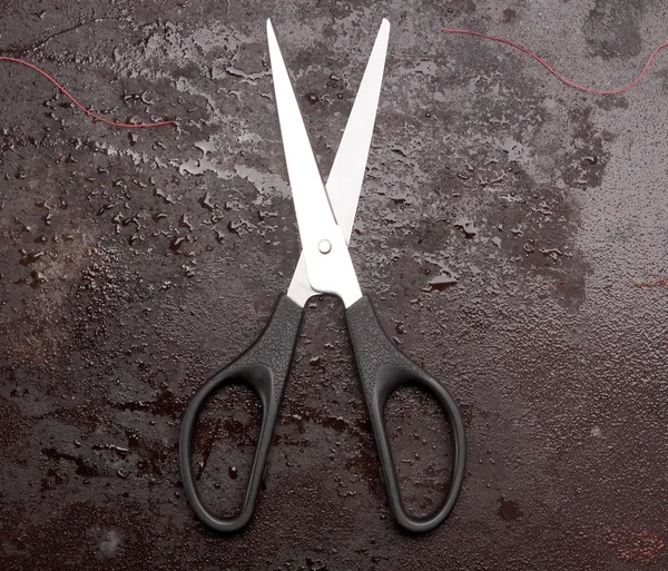 Scissors and a red thread Royalty Free Stock Photos