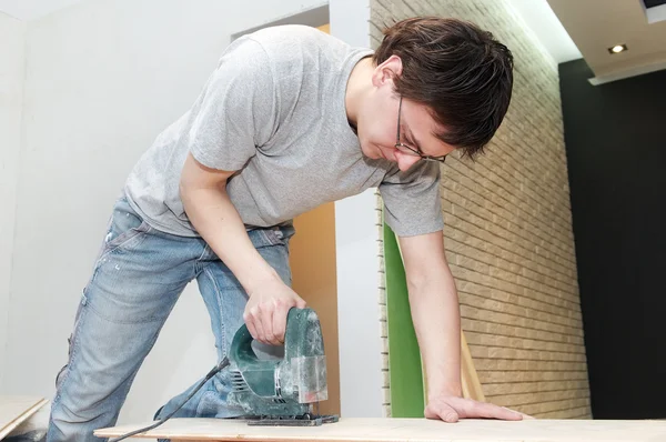 Worker cutting floor board with jigsaw — Stock Photo, Image
