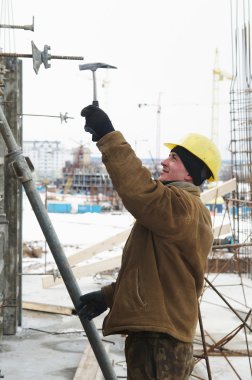 Worker with hammer assembling formwork clipart