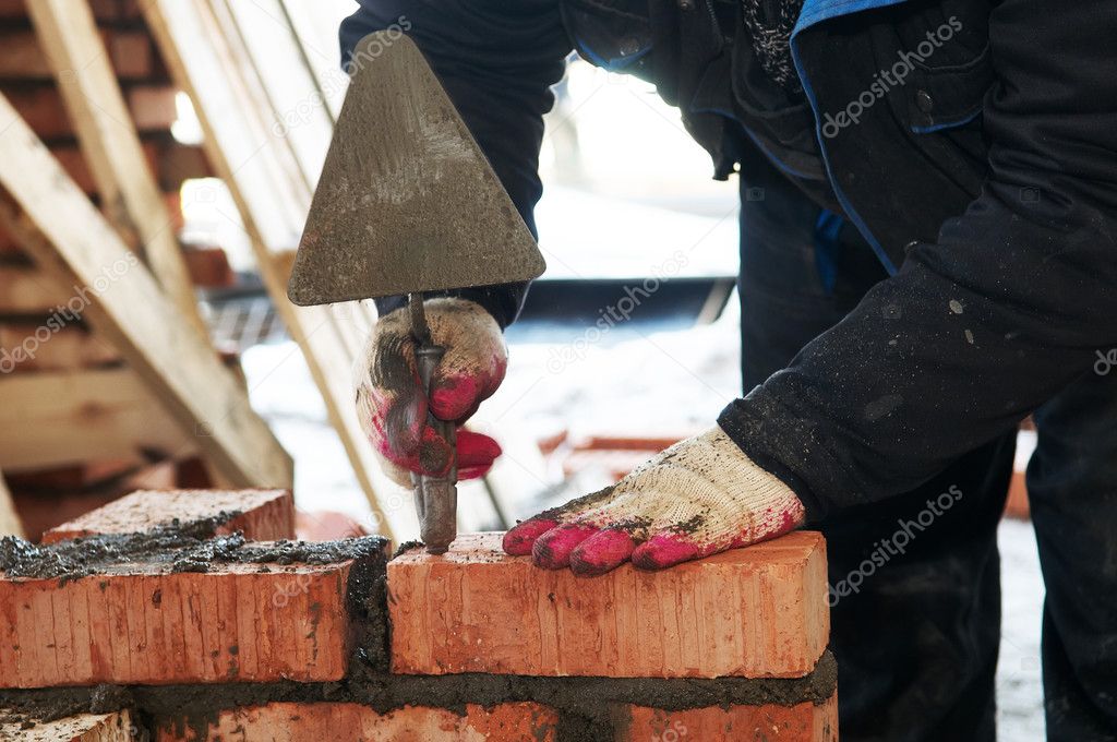 Hands of a mason at bricklaying work