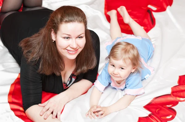 Молодая мать и маленький ребенок, лежащие на кровати — стоковое фото