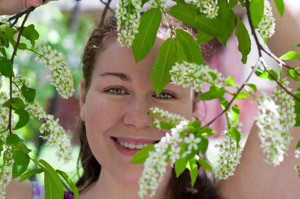 Mujer joven oliendo flor en rama de árbol — Foto de Stock