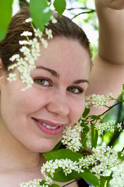 Jovem mulher cheirando flor no ramo da árvore — Fotografia de Stock