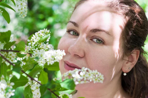 Νεαρή γυναίκα που μυρίζει λουλούδι στο κλαδί του δέντρου — Φωτογραφία Αρχείου