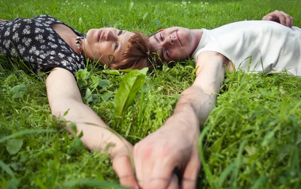 Young loving couple teenagers laying on grass — Stock Photo, Image