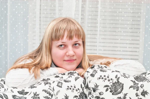 Blondinen flickan har kombinerat händer på en soffa — Stockfoto